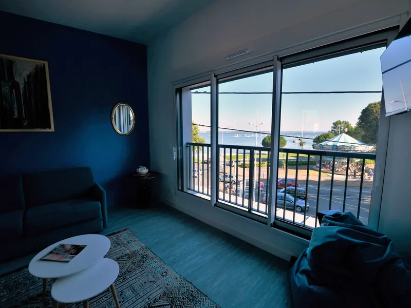 Salon de La Pêcherie : mur bleu et vue sur la mer par la baie vitrée
