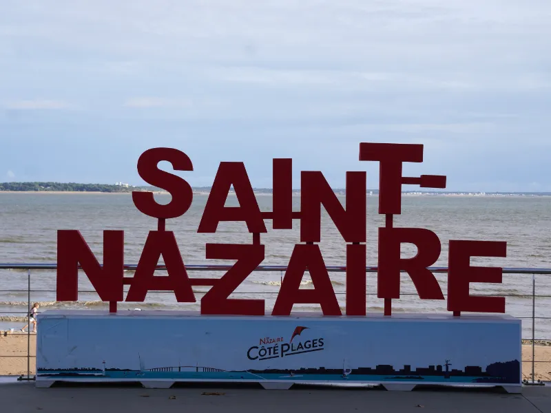 Les lettres rouges SAINT-NAZAIRE sur la promenade du front de mer, devant la plage et l'estuaire