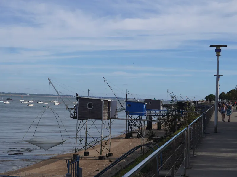 Les carrelets sur pilotis le long de la promenade du front de mer, voiliers au mouillage